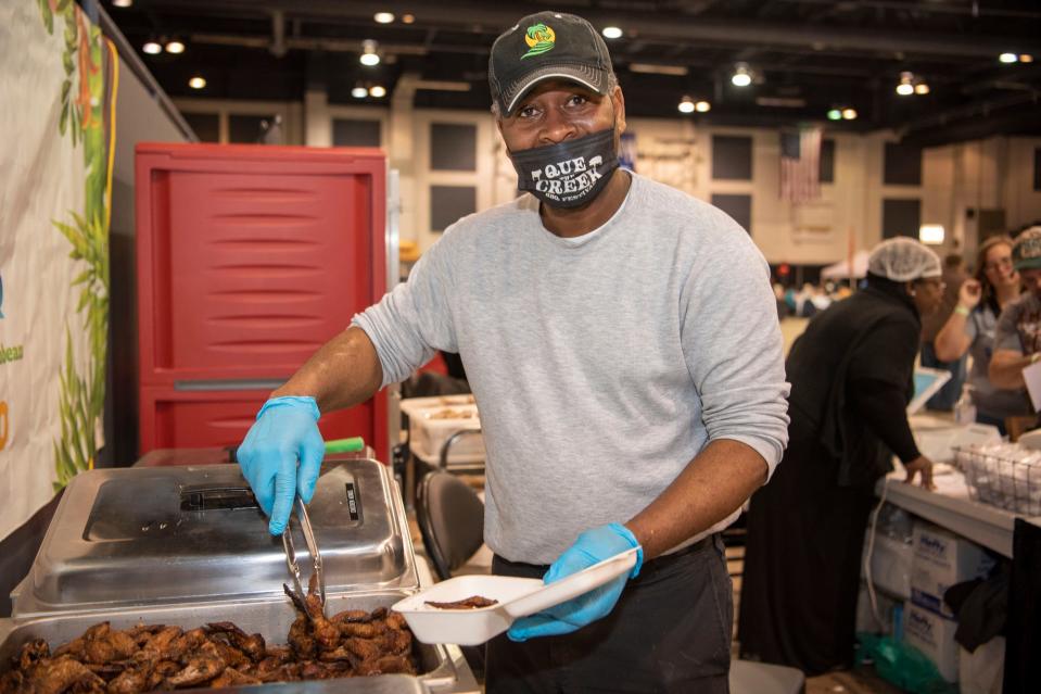 Juliano Jean-Jules, owner of Island Style BBQ, serves barbecue dishes during Que the Creek BBQ Festival at Kellogg Arena in Battle Creek on Saturday, Feb. 5, 2022.