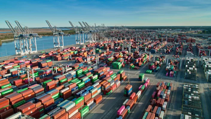 Aerial shot of the Port of Savannah in Georgia on a clear evening in Fall, with a densely packed intermodal container yard and cranes reaching out over ships docked in the Savannah River. This shot was taken during the global supply chain crisis, and the terminal is visibly at capacity. 

Authorization was obtained from the FAA for this operation in restricted airspace.