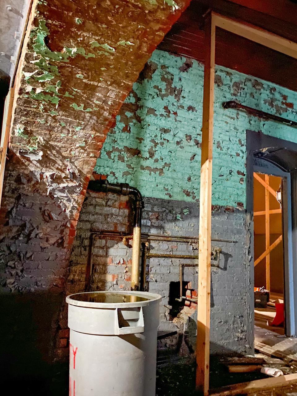 A plastic garbage can is full of water dripping from the exposed brick in an upper floor at the Bank Street Armory in Fall River.