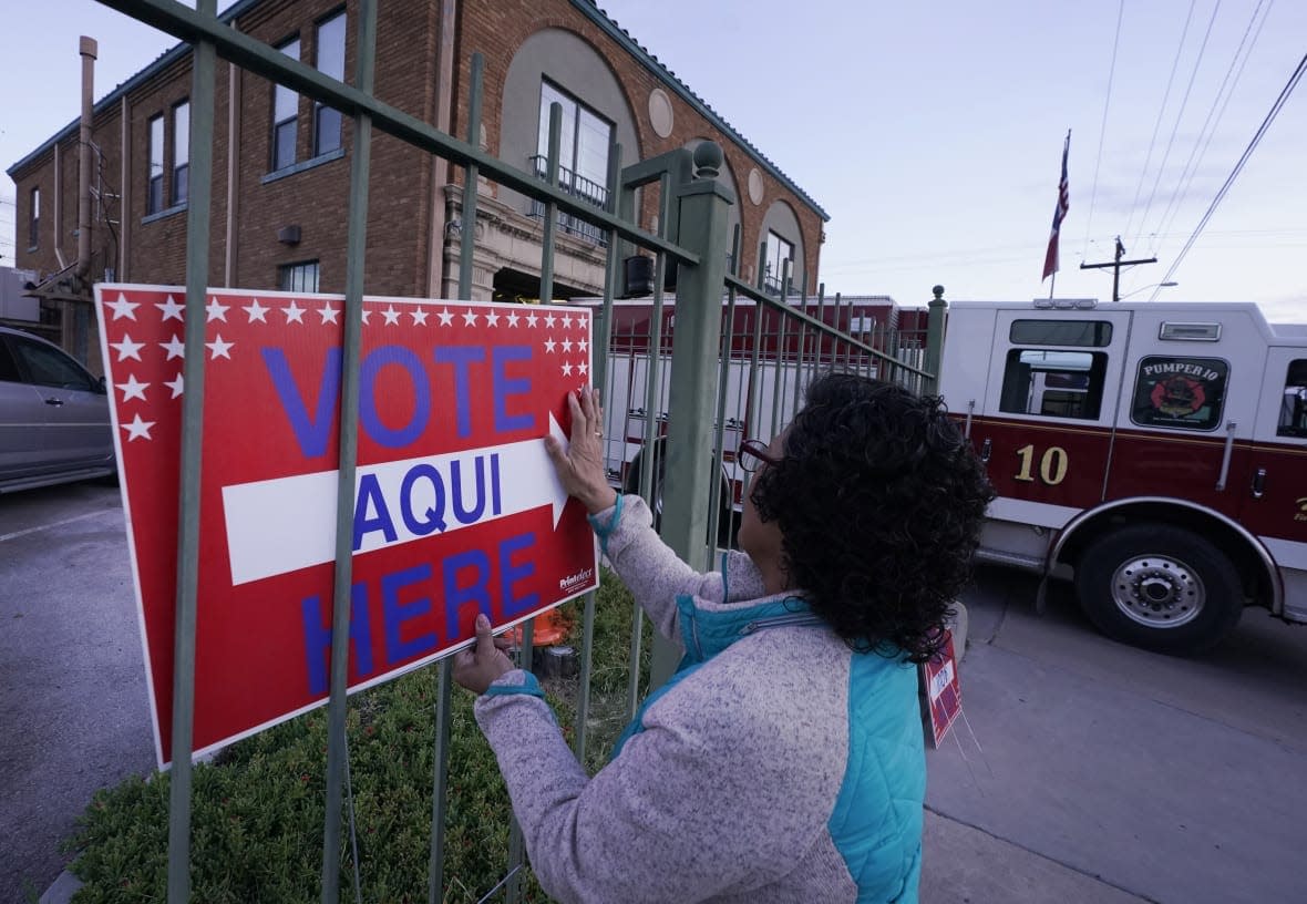 Election worker Ramona Ortiz places a sign outside a polling station at Fire Station 3 on E. Rio Grande Ave in El Paso, Texas, just before polls open on Nov. 8, 2022. (AP Photo/LM Otero, File)