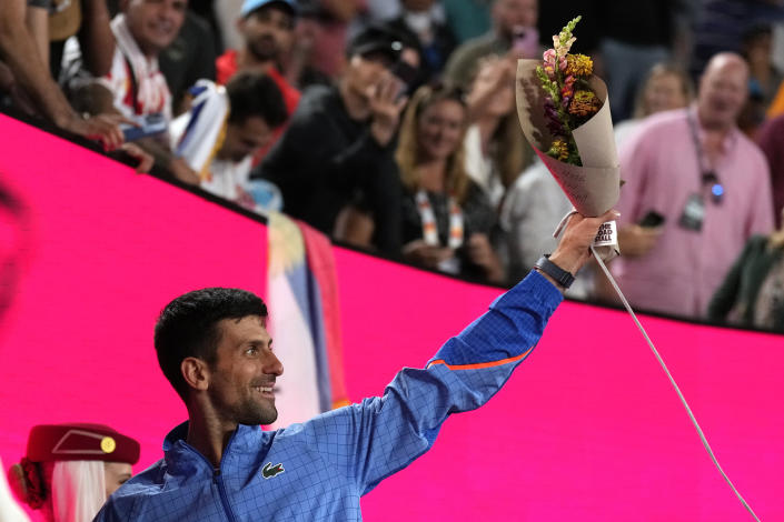 Novak Djokovic of Serbia holds up flowers as he leaves Rod Laver Arena after defeating Andrey Rublev of Russia in their quarterfinal match at the Australian Open tennis championship in Melbourne, Australia, Wednesday, Jan. 25, 2023. (AP Photo/Ng Han Guan)