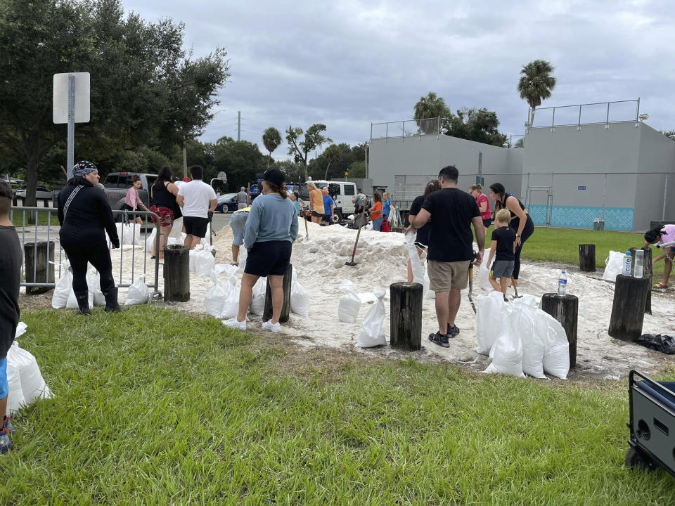 Varias personas llenan sacos con arena en MacFarlane Park, en Tampa, Florida, el domingo 25 de septiembre de 2022. (Luis Santana/Tampa Bay Times vía AP)