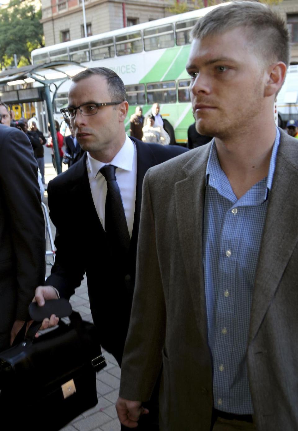 Oscar Pistorius, left, accompanied by an unidentified relative, walks towards the high court in Pretoria, South Africa, Wednesday, May 14, 2014. The chief prosecutor in the murder trial of Pistorius on Tuesday asked that the double-amputee runner be placed under psychiatric evaluation after an expert witness testified that he had an anxiety disorder. Pistorius is charged with murder for the shooting death of his girlfriend, Reeva Steenkamp, on Valentines Day in 2013. (AP Photo/Themba Hadebe)
