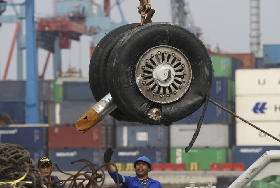 FILE - In this Saturday, Nov. 3, 2018, file photo, a crane moves a pair of wheels recovered from the Lion Air jet that crashed into the Java Sea for further investigation at Tanjung Priok Port in Jakarta, Indonesia. Indonesia's transport safety board chair said during a press conference, Thursday, March 21, 2019, that a third pilot was in the cockpit of penultimate Lion Air flight before the crash. (AP Photo/Achmad Ibrahim, File)