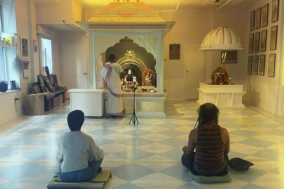 Priest Prakash, center, livestreams the Lord Shiva puja, which occurs every Thursday, at Broome Street Ganesha Temple in the Manhattan borough of New York on Sept. 14, 2023. Founded by yoga teacher Eddie Stern in 2001, the temple pitches itself not strictly as a Hindu house of worship but as a sanctuary where passersby can find a few minutes of peace amid the chaos of New York. (Richa Karmarkar/RNS via AP)