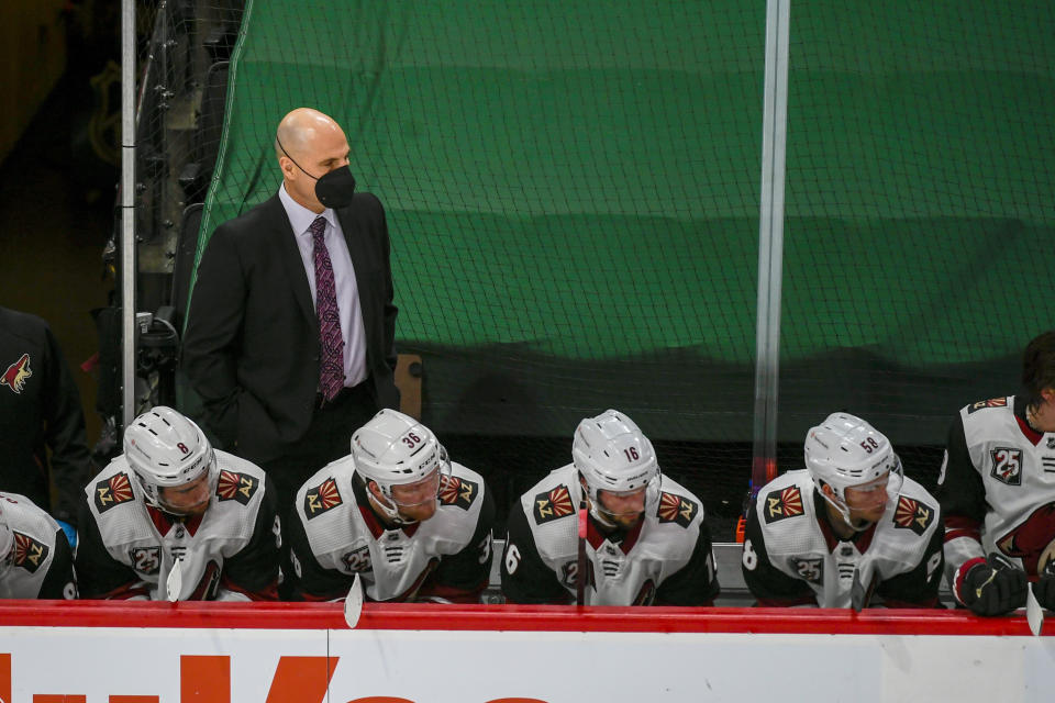 Arizona Coyotes head coach Rick Tocchet, standing, watches the game during the second period of an NHL hockey game Wednesday, April 14, 2021, in St. Paul, Minn. The Wild won 5-2. (AP Photo/Craig Lassig)