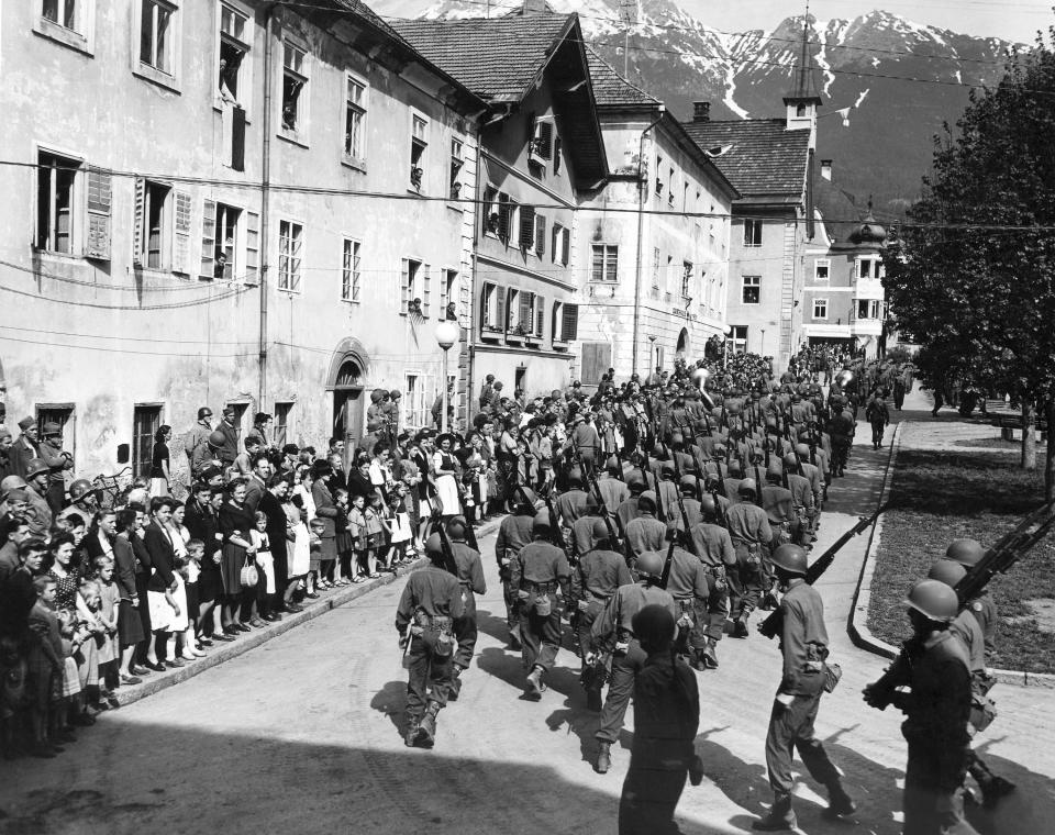 FILE - In this May 8, 1945 file photo the 44th Infantry Division, U.S. Seventh Army, parades on VE Day through the town square of Imst, Austria. On Friday's 75th anniversary of the end of World War II in Europe, talk of war is afoot again — this time against a disease that has killed at least a quarter of a million people worldwide. Instead of parades, remembrances and one last great hurrah for veterans now mostly in their nineties, it is a time of lockdown and loneliness, with memories bitter and sweet (AP Photo, File)