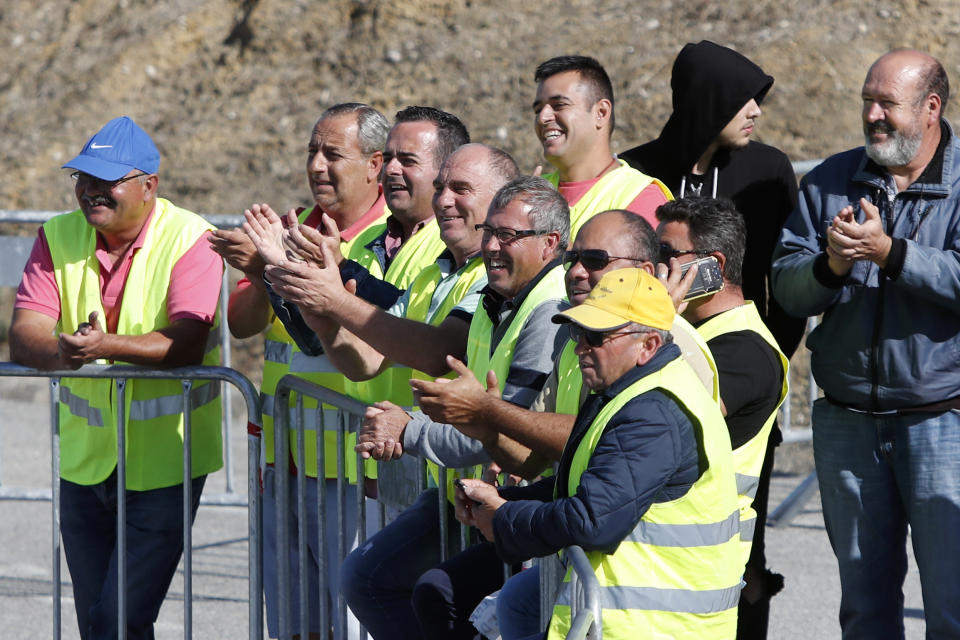 Tanker truck drivers on strike applaud a fellow driver leaving a fuel depot in Aveiras, outside Lisbon, Monday, Aug. 12, 2019. Portugal is rationing gas as a precaution after some 2,000 tanker truck drivers began an open-ended strike over pay on Monday. The government has set a limit of 25 liters (6.6 gallons) for customers at gas stations until further notice. (AP Photo/Armando Franca)