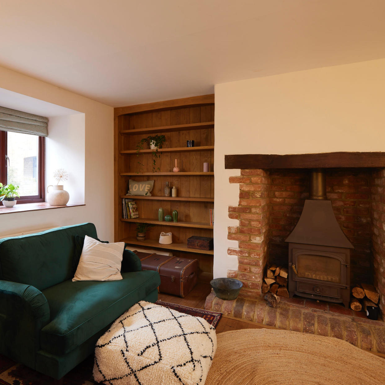  Living room with green armchair and pouffe in front of woodturning fireplace. 