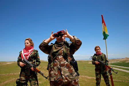 Iraqi Kurdish female fighter Haseba Nauzad looks through a pair of binoculars during a deployment near the frontline of the fight against Islamic State militants in Nawaran near Mosul, Iraq, April 20, 2016. REUTERS/Ahmed Jadallah