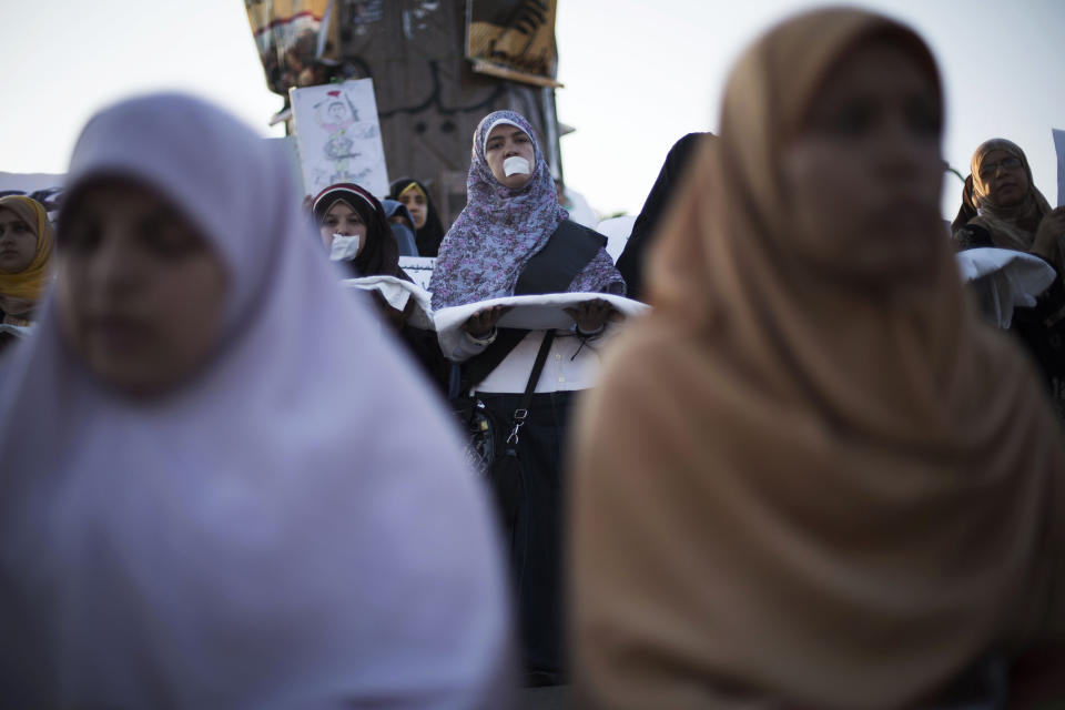 A woman supporter of Egypt's ousted President Mohammed Morsi, with tape on her mouth is seen while holding a shroud during a protest near Cairo University in Giza, Egypt, Thursday, August, 1, 2013. (AP Photo/Manu Brabo)