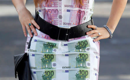 FILE PHOTO: A woman wears a home-made dress featuring imitation 100 and 500 euro notes as she walks in Bordeaux, southwestern France, November 7, 2014. REUTERS/Regis Duvignau/File Photo