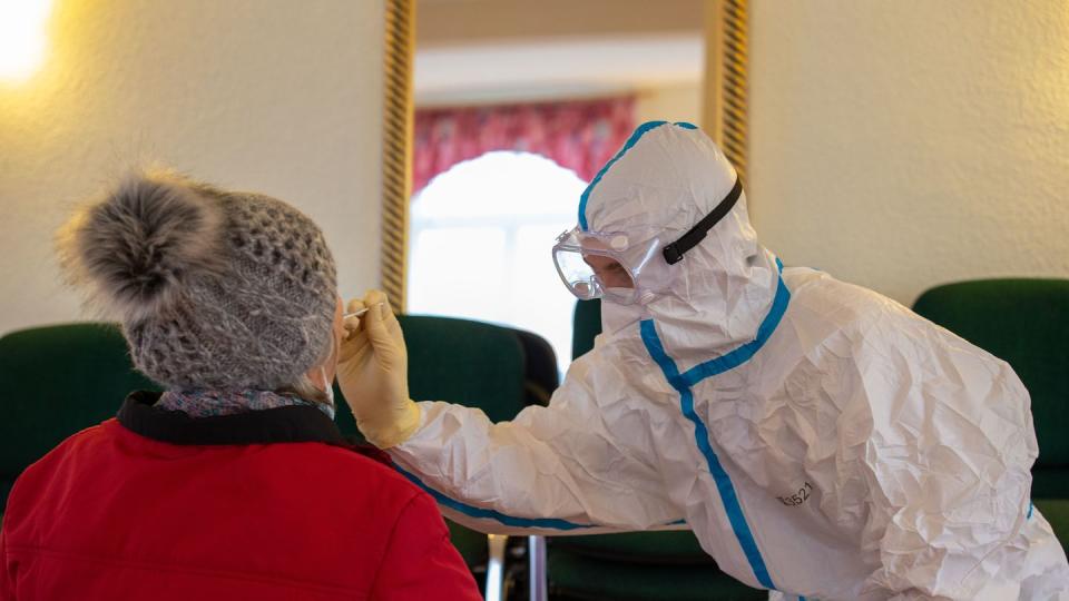 Ein Mitarbeiter des Gesundheitswesens nimmt von der einer älteren Dame einen Rachenabstrich.