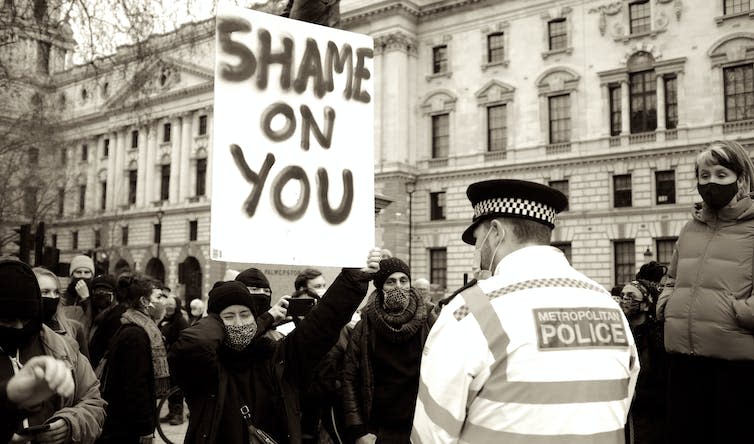 Protesters with a banner in front of a policeman