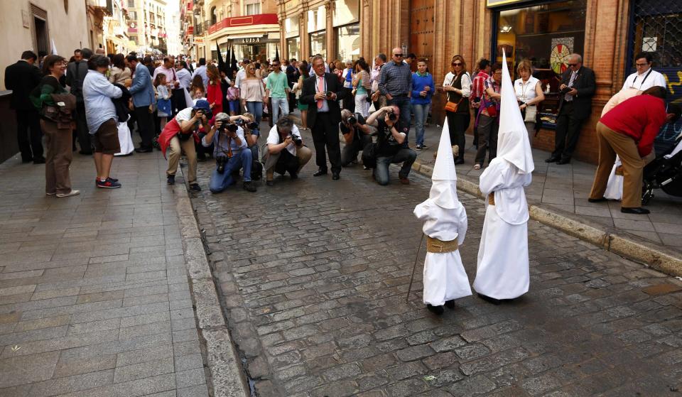 Photographers take pictures of penitents of "La Borriquita" brotherhood on Palm Sunday in the Andalusian capital of Seville, southern Spain, April 13, 2014. Holy Week is celebrated in many Christian traditions during the week before Easter. REUTERS/Marcelo del Pozo (SPAIN - Tags: RELIGION SOCIETY)