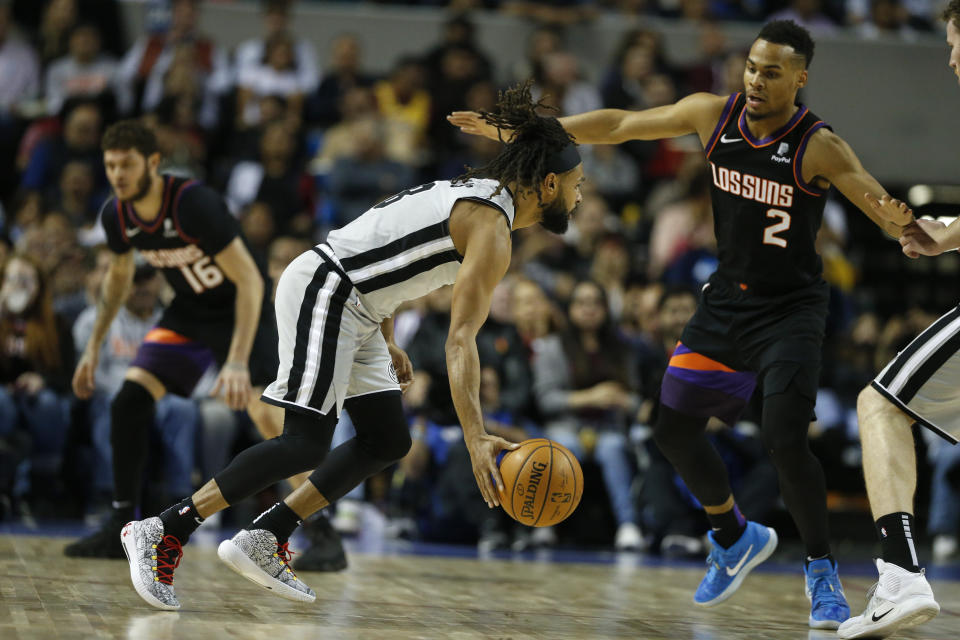 Patty Mills, de los Spurs de San Antonio, intenta driblar a Elie Okobo, de los Suns de Phoenix, el sábado 14 de diciembre de 2019, durante un partido de la NBA en la Ciudad de México (AP Foto/Rebecca Blackwell)