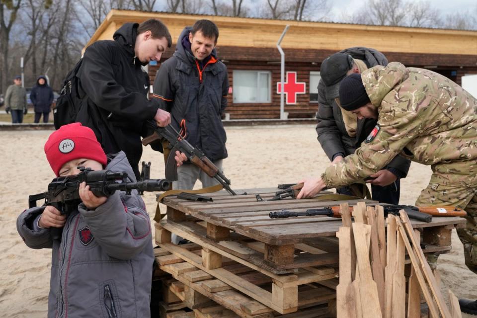 A boy plays with a weapon as an instructor shows a Kalashnikov assault rifle while training members of a Ukrainian far-right group train, in Kyiv, Ukraine (AP)