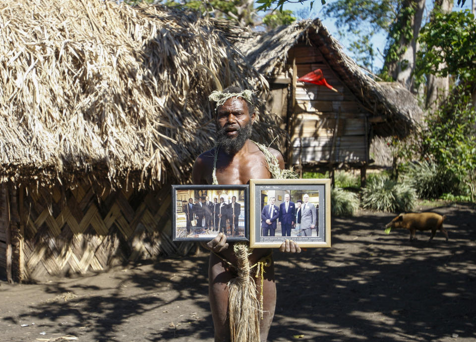 FILE - In this Sunday, May 31, 2015 file photo, Albi Nagia poses with photographs of Prince Philip in Yakel, Tanna island, Vanuatu. A tribe in the remote island nation of Vanuatu who saw Prince Philip as a god will greet his death with ritual wailing and ceremonial dancing, an expert said. The group, based in villages on the island of Tanna in the former Anglo-French colony, revered the Duke of Edinburgh and believed him to be a reincarnation of an ancient warrior who left the island to fight a war. (AP Photo/Nick Perry, File)