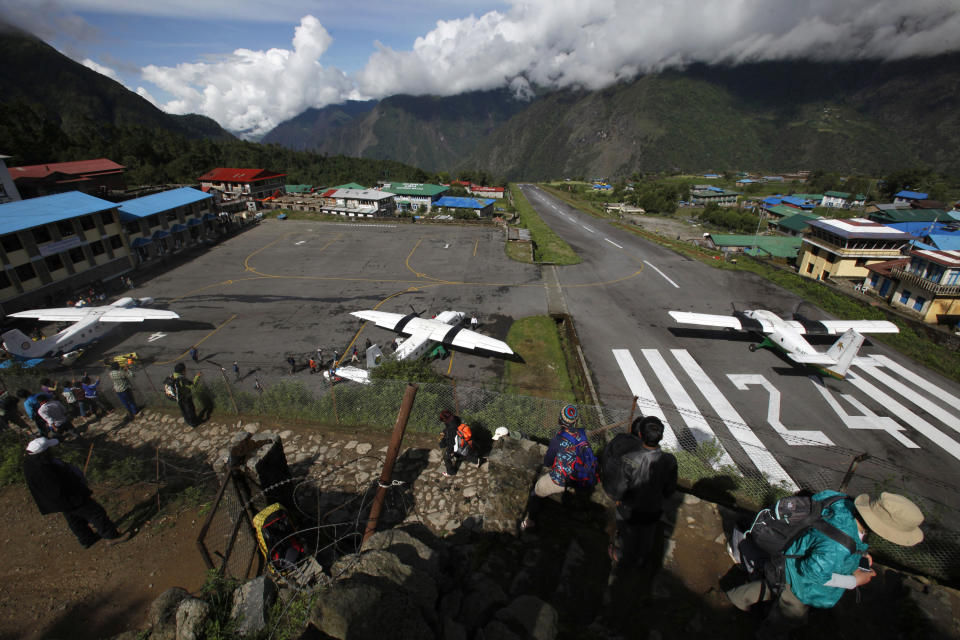 In this Sunday, May 26, 2013 photo, several flights get ready to take off after a couple of days of bad weather disrupted flight services at Lukla airport, Nepal. Carved out of side of a mountain, the airport was built by Sir Edmund Hillary in 1965, and at an altitude of 2,843 meters (9,325 feet) it has earned the reputation of being one of the most extreme and dangerous airports in the world. (AP Photo/Niranjan Shrestha)