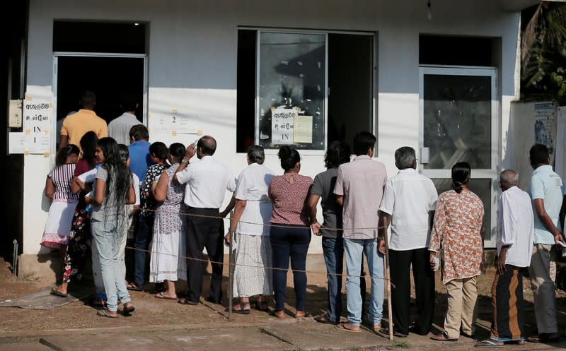 People stand in a line to cast their vote during the presidential election in Colombo