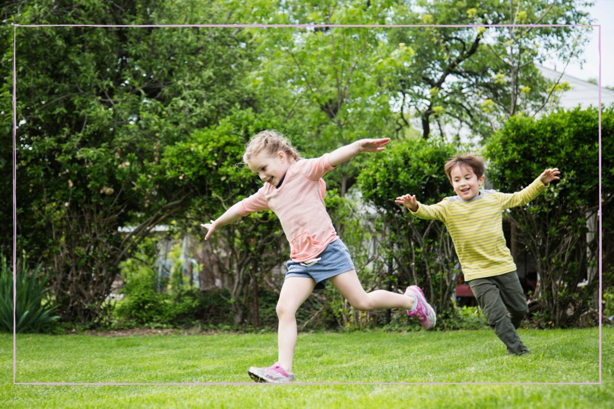  Two children running around in a garden with arms out wide. 