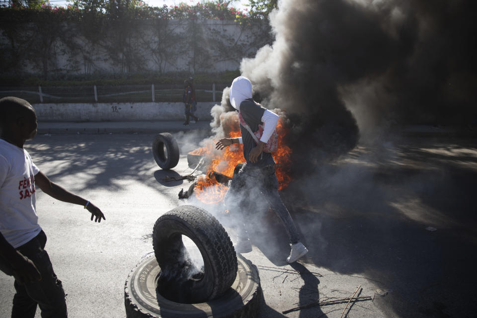 Burning tires block a street where they were placed by factory workers protesting for salary increases in Port-au-Prince, Haiti, Wednesday, Feb. 23, 2022. It is the first day of a three-day strike organized by factory workers who also shut down an industrial park earlier this month to protest pay. (AP Photo/Odelyn Joseph)