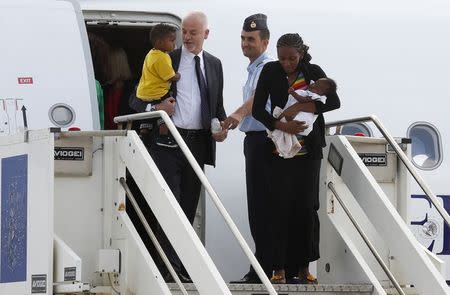 Mariam Yahya Ibrahim of Sudan (R) holds one of her children next to Lapo Pistelli (L), Italy's vice minister for foreign affairs, holding her other child, as they land at Ciampino airport in Rome July 24, 2014. REUTERS/Remo Casilli