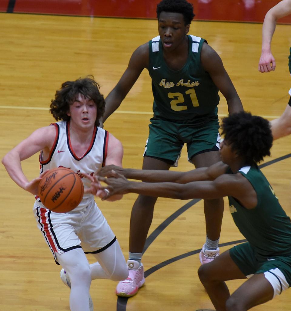 Gabriel Sweat of Monroe pressured by Kaleb Brown and Macari Moore of Ann Arbor Huron passes off Tuesday during a 58-27 Trojan loss.