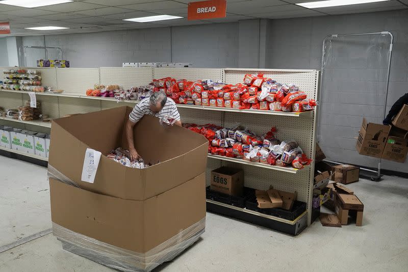 A volunteer at the Community Food Center, helps to restock bread on the shelves in Stone Mountain