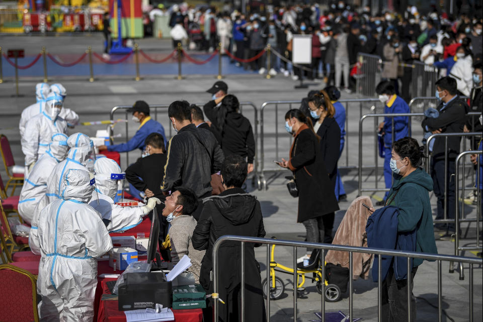 In this photo released by Xinhua News Agency, residents line up to receive a swab for the coronavirus test during a mass testing in Xixia District of Yinchuan in northwest China's Ningxia Hui Autonomous Region Saturday, Oct. 23, 2021. China's Gansu has closed all tourist sites following the reporting of new COVID-19 cases in the northwestern province. Gansu lies along the ancient Silk Road and is famed for the Dunhuang grottoes filled with Buddhist images and other ancient religious sites. (Feng Kaihua/Xinhua via AP)