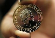 A gallery assistant holds a 2-pound coin with the new portrait of Britain's Queen Elizabeth following it's unveiling at the National Portrait Gallery in London March 2, 2015. REUTERS/Suzanne Plunkett