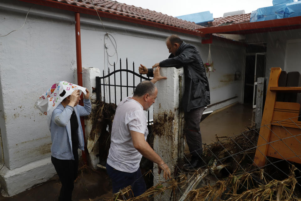 Antonis Ginos, top, tries to enter his flooded house following by his relative Panagiotis Chrysalis in the village of Nea Lefki, near Larissa, central Greece, Wednesday, Sept. 6, 2023. Severe rainstorms that lashed parts of Greece, Turkey and Bulgaria have caused several deaths as rescuers continue searching for missing people. (AP Photo/Vaggelis Kousioras)
