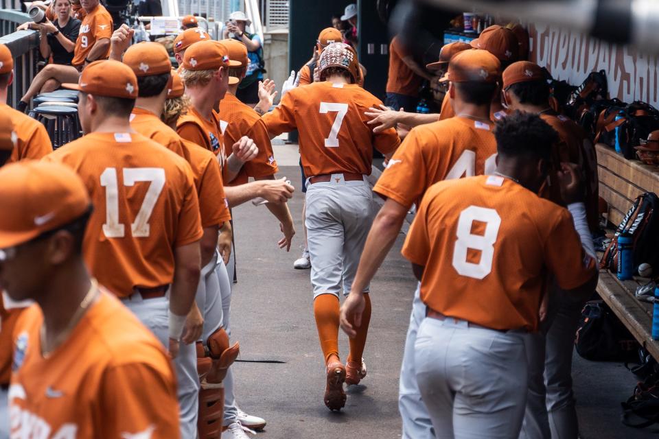 Texas center fielder Douglas Hodo III, center, is greeted by teammates in the UT dugout after scoring a run Sunday against Texas A&M. But it was the Aggies who won 10-2, ending the Longhorns' season at the College World Series.
