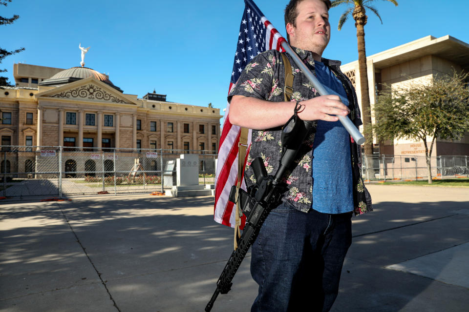 “GA”, a member of the Boogaloo Boys, stands with his assault rifle in front of the Arizona State Capitol building on January 17, 2021 in Phoenix, Arizona. - Credit: Sandy Huffaker/Getty Images