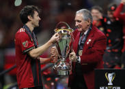 Atlanta United owner Arthur Blank, right, hands the trophy to team captain Michael Parkhurst (3) after the MLS Cup championship soccer game against the Portland Timbers, Saturday, Dec. 8, 2018, in Atlanta. Atlanta United won 2-0. (AP Photo/Todd Kirkland)