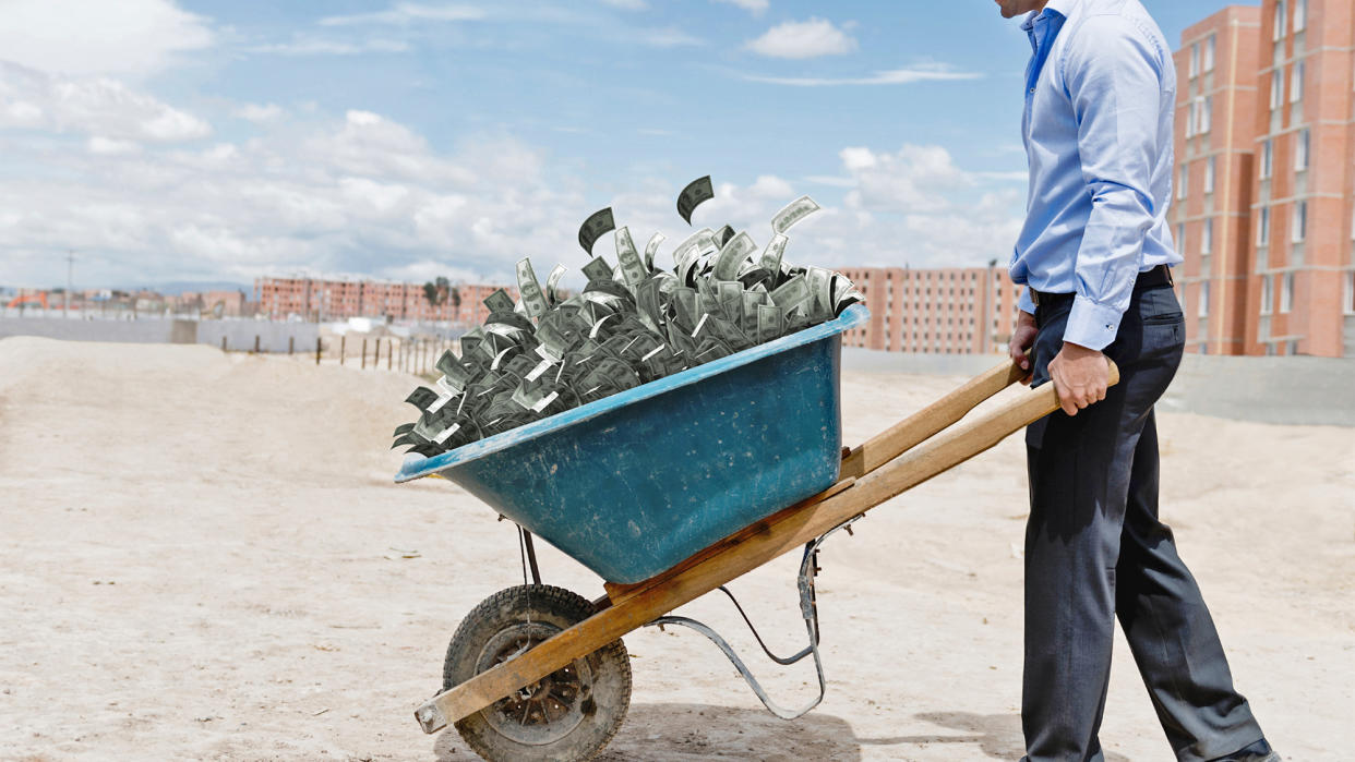 Man with wheelbarrow full of money