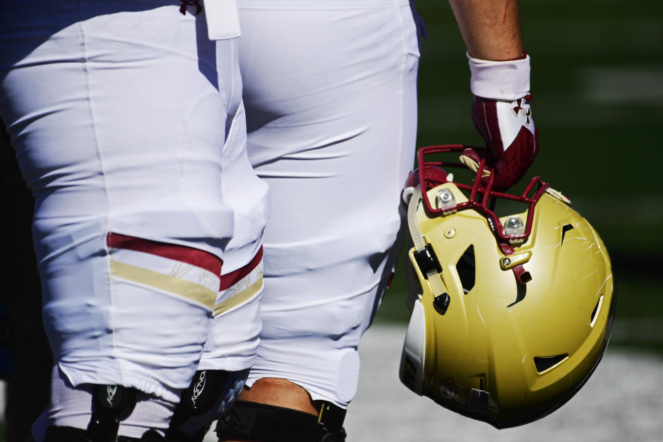 A Boston College football player holds his helmet by his leg.