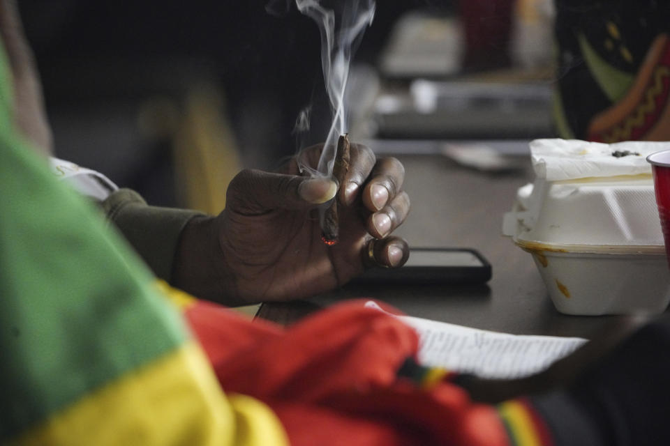 A Rastafari attendee holds a cannabis cigarette during an event by the Rastafari Coalition marking the 91st anniversary of the coronation of the late Ethiopian Emperor Haile Selassie I in Columbus, Ohio on Tuesday, Nov. 2, 2021. As public opinion and policy continues to shift in the U.S. and across the world towards the use of marijuana, some adherents of Rastafari question their place in the future of the herb that they consider sacred. (AP Photo/Emily Leshner)