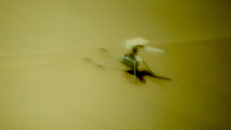 a small dual-rotor helicopter sits motionless on a sand dune