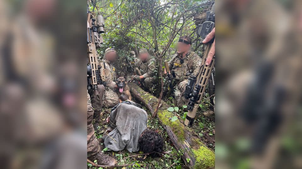 Danilo Cavalcante is seen lying in the woods surrounded by officers and Yoda, a US Border Patrol BORTAC K9, on Wednesday. - US Border Patrol Special Operations Group