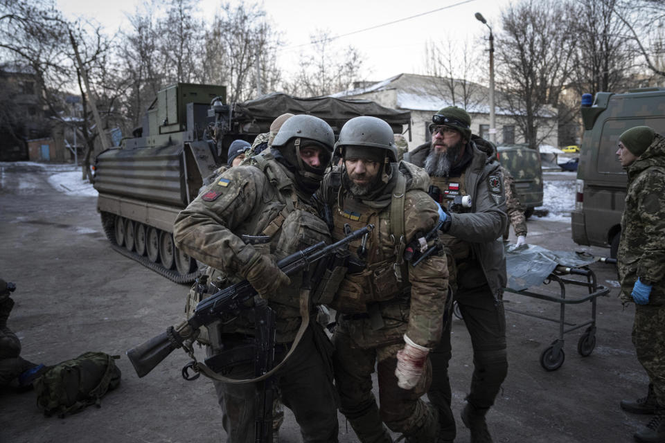 A Ukrainian serviceman carries his injured comrade evacuated from the battlefield into a hospital in Donetsk region, Ukraine, Monday, Jan. 9, 2023. (AP Photo/Evgeniy Maloletka)