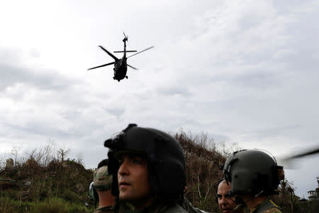 An HH-60 Blackhawk helicopter from 101st Airborne Division's "Dustoff" unit takes off behind Crew Chief Alexander Blake and his fellow soldiers during recovery efforts following Hurricane Maria, in Morovis, Puerto Rico, October 5, 2017. REUTERS/Lucas Jackson