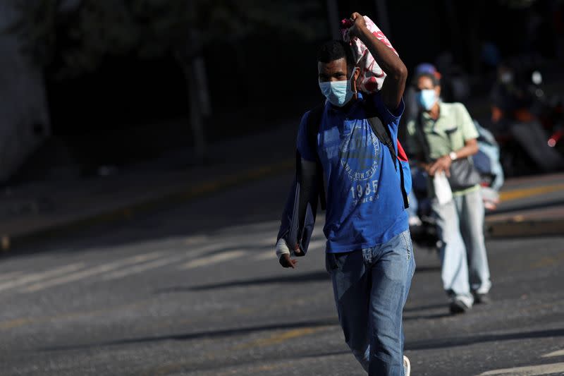 People wearing protective masks walk in the street during the first day of a national quarantine in response to the spreading coronavirus disease (COVID-19), in Caracas