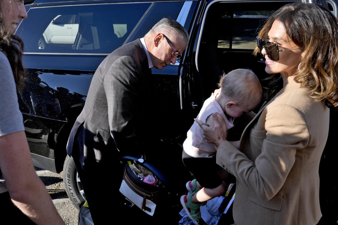 Actor Alec Baldwin and his wife, Hilaria Baldwin, holding a baby, get out of a vehicle.