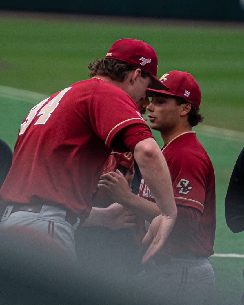 Former Shrewsbury High star John West, left, is greeted by former St. John's star Tyler Mudd, right, as he comes off the field during a recent game for Boston College.