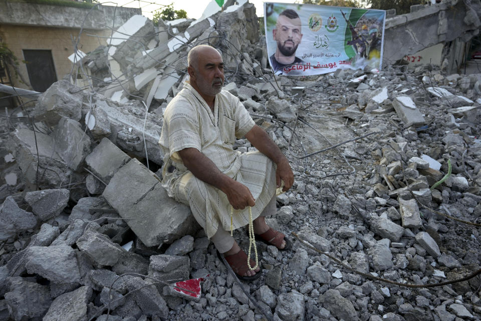 A Palestinian sits in the rubble of the house of Asad Rifai after it was demolished by Israeli forces along with the house of of Subhi Sbeihat, both suspected of carrying out a deadly May 2022 attack on Israelis in the city of Elad, near Tel Aviv, in Rummana, near the West Bank city of Jenin, Monday, Aug. 8, 2022. The Israeli military says their soldiers faced a violent protest during the operation. (AP Photo/Majdi Mohammed)