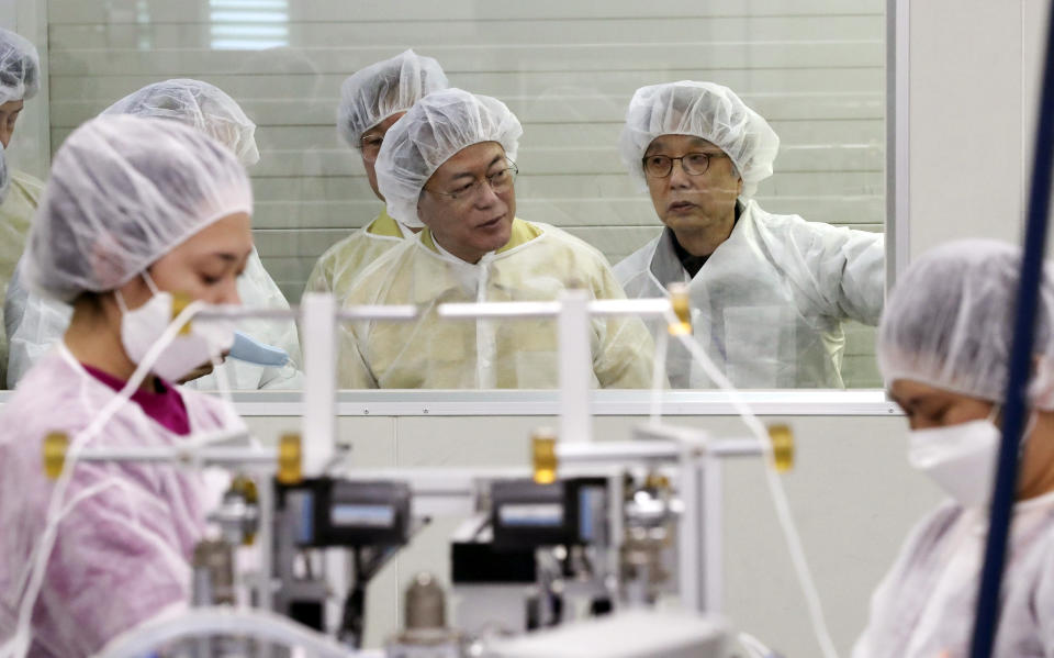 South Korean President Moon Jae-in, rear center, looks around the production line of mask at Wooil C&Tech in Pyeongtaek, South Korea, Friday, March 6, 2020. North Korea said Friday it has released about 220 foreigners from a quarantine imposed as part of its vigilant prevention efforts to avoid an outbreak of the coronavirus that has spread around the world. (Lee Jin-wook/Yonhap via AP)