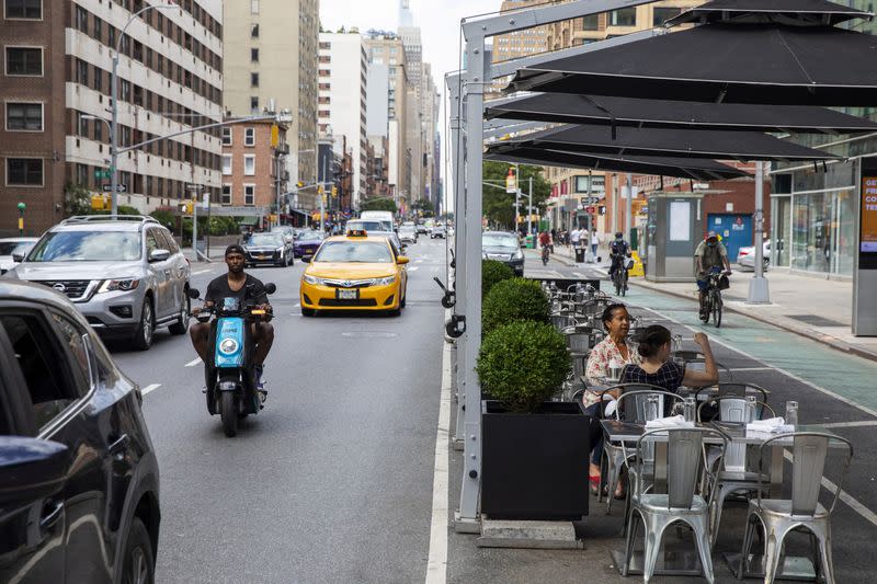 Customers sit in outdoor seating that is placed in parking spaces to follow health protocols for restaurants to slow the spread of Coronavirus (COVID-19) outside of a restaurant in New York City, New York