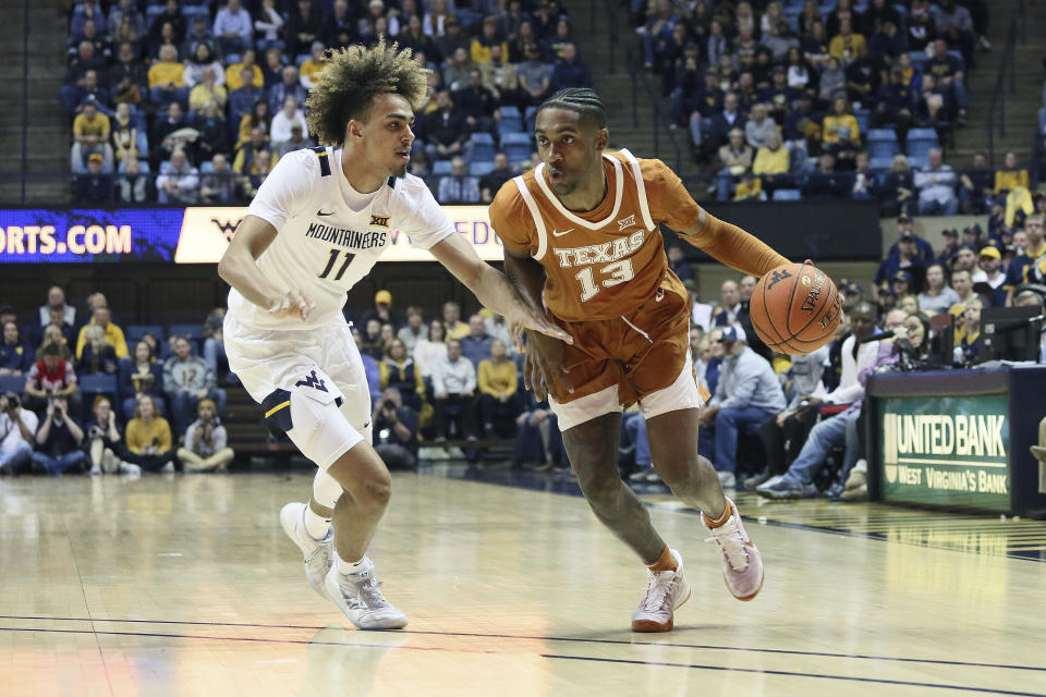 Texas guard Jase Febres (13) drives it up court as he is defended by West Virginia forward Derek Culver (1) during the first half of an NCAA college basketball game Monday, Jan. 20, 2020, in Morgantown, W.Va. (AP Photo/Kathleen Batten)