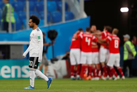 Soccer Football - World Cup - Group A - Russia vs Egypt - Saint Petersburg Stadium, Saint Petersburg, Russia - June 19, 2018 Egypt's Mohamed Salah looks dejected as Russia players celebrate their first goal scored by Egypt's Ahmed Fathy with an own goal REUTERS/Lee Smith